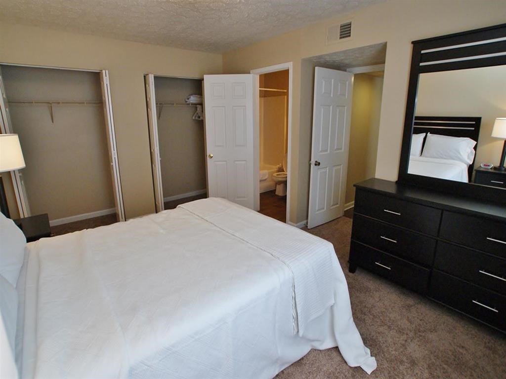 a bedroom with a white bed and a mirror