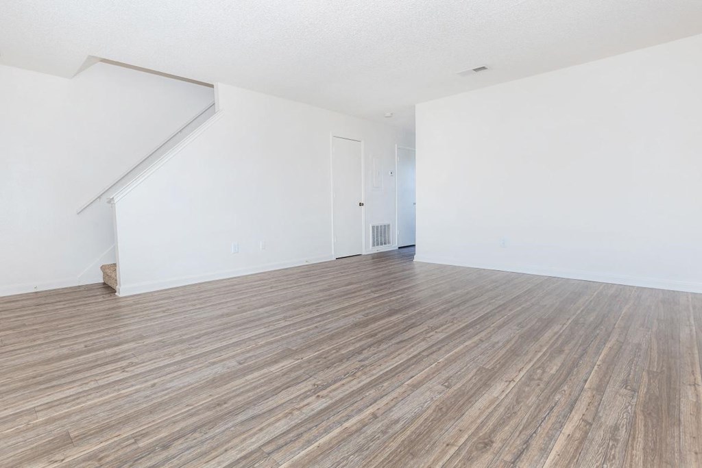 an empty living room with white walls and wood floors
