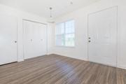 an empty living room with a wood floor and white walls