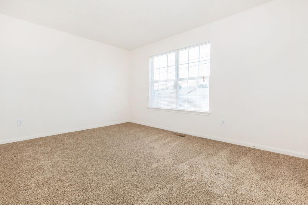 an empty room with carpet and a window