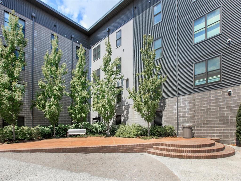 a courtyard in front of a building with trees and a bench