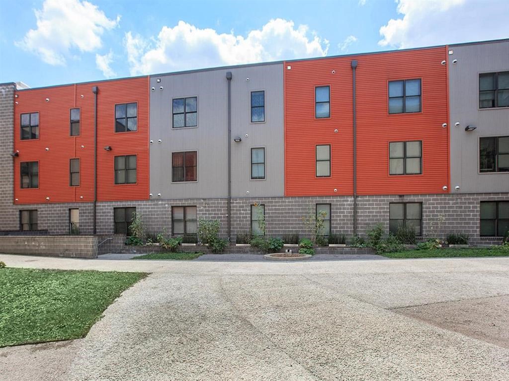 the exterior of an apartment building with a sidewalk and grass