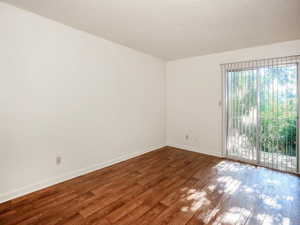 an empty living room with a wood floor and a sliding glass door