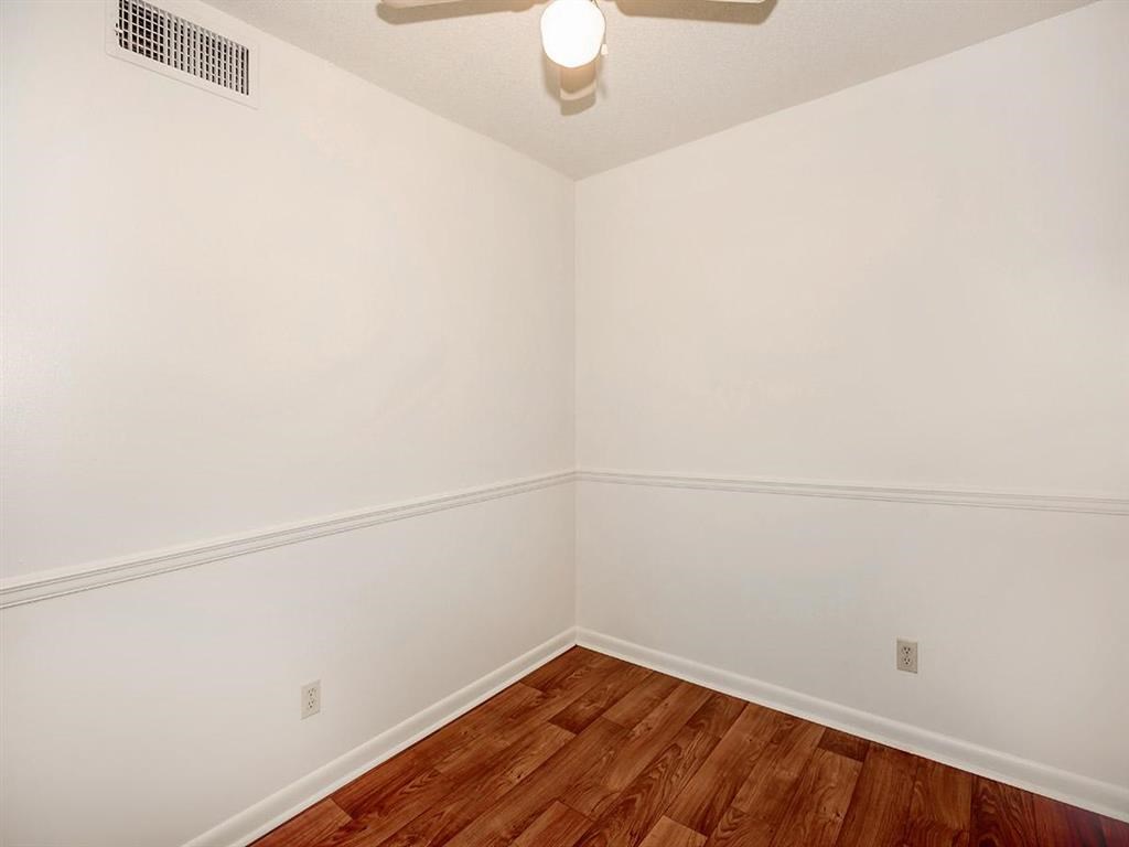 a room with a wood floor and white walls and a ceiling fan