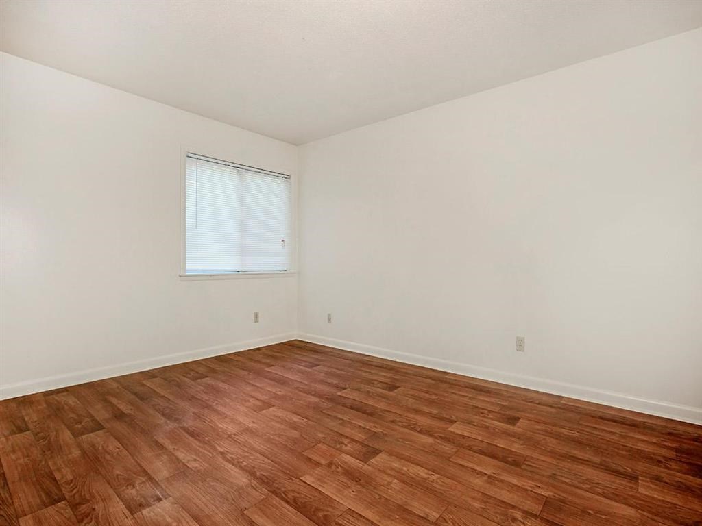 an empty room with wood floors and a window