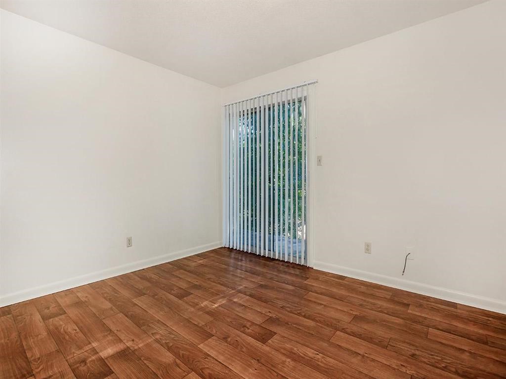 an empty living room with wood floors and a window