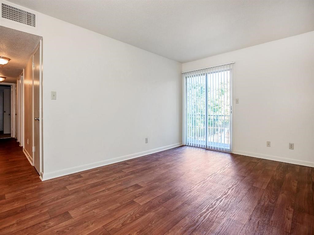 an empty living room with wood floors and a sliding glass door