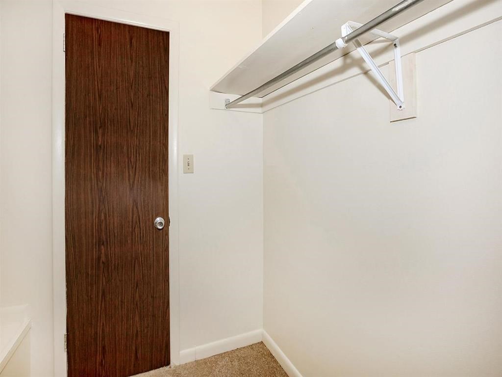 a closet with a wooden door in a white room with a white wall and