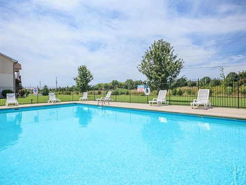 a large swimming pool with white chairs around it