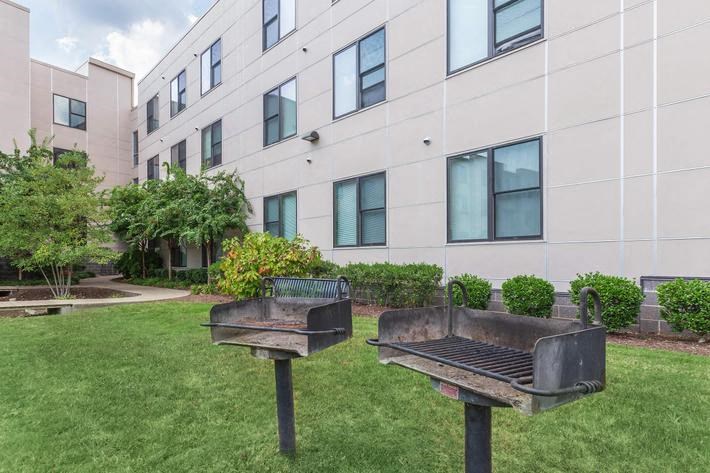 two grills in the grass in front of an apartment building