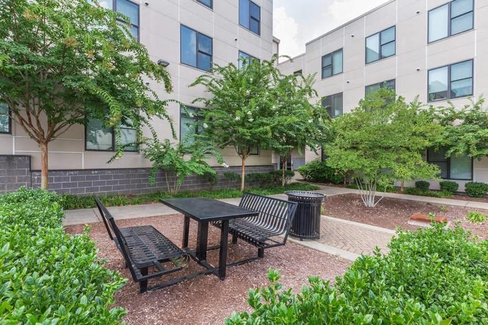 a courtyard with a table and chairs in front of an apartment building