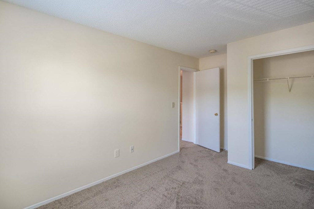 an empty bedroom with a closet and a door to a hallway