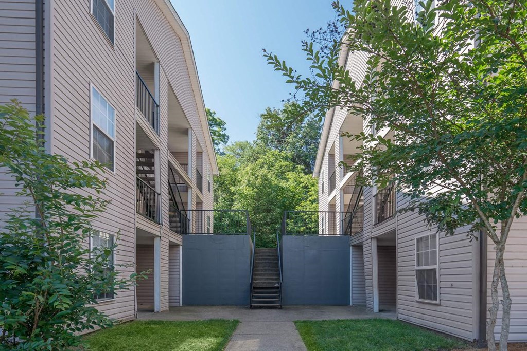 a courtyard between two apartment buildings with stairs and a fence