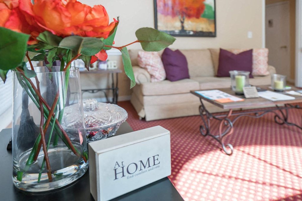 a living room with a vase of flowers and a home sign