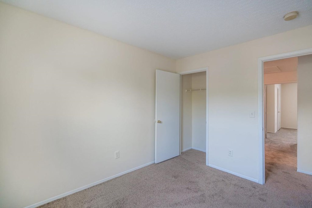 a bedroom with a carpeted floor and a door to a closet