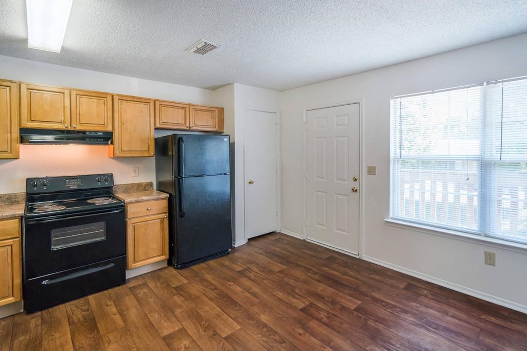 a kitchen with a black refrigerator and a wooden floor