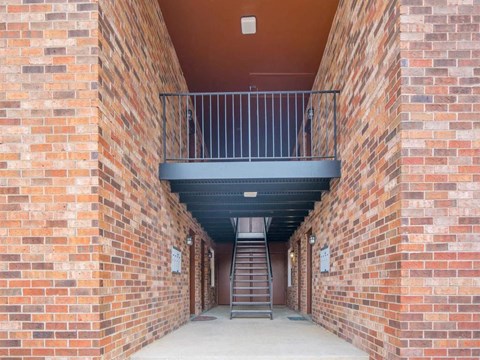 a corridor of brick walls with a staircase