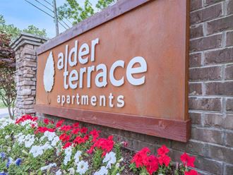 a sign for elder terrace apartments with flowers around it