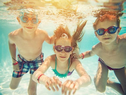three young children swimming underwater in a swimming pool