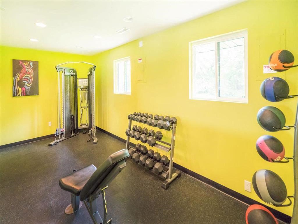 a gym with a yellow wall and a chair and dumbbells