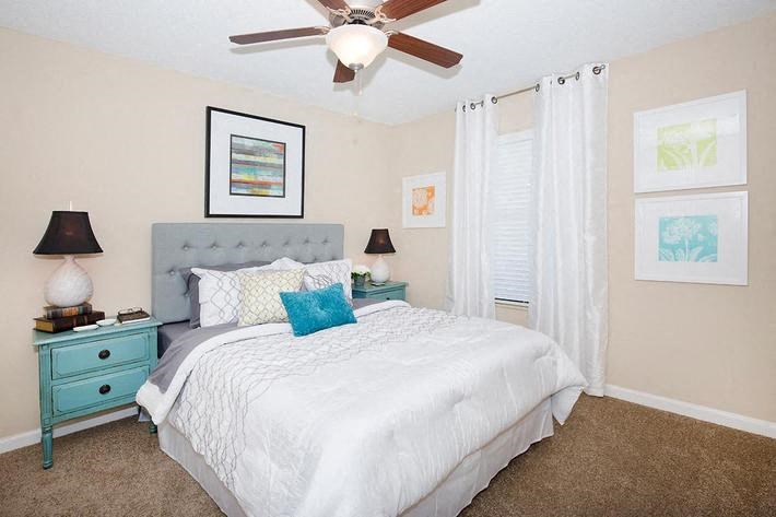 a bedroom with a white bed and a ceiling fan