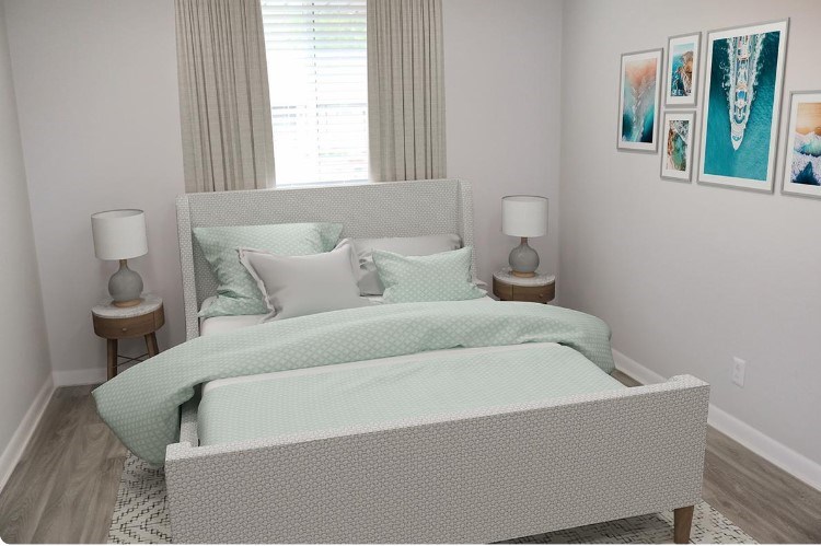 A bed with a white headboard and a green blanket is in the center of the room.