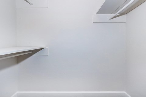 a corner of a room with white walls and a shelf