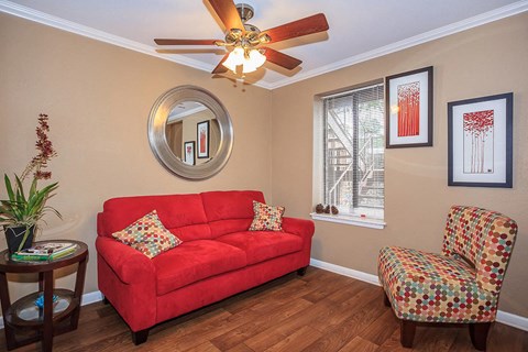 a living room with a red couch and a ceiling fan