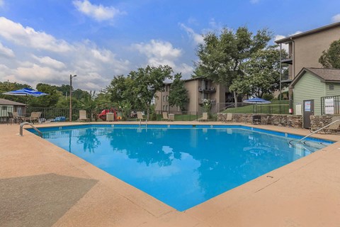 a swimming pool with trees and buildings in the background
