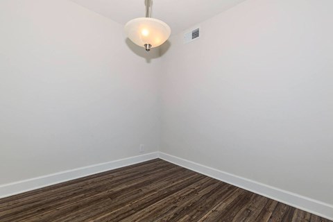 a room with white walls and wood floors and a lamp on the wall