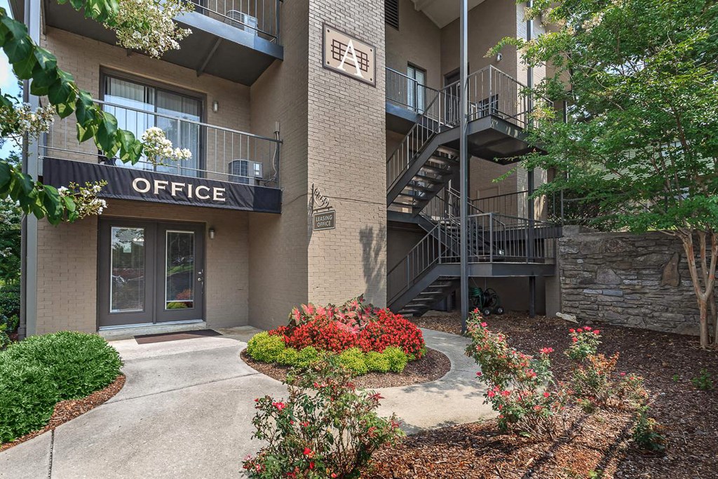 the entrance to an office building with a sidewalk and plants
