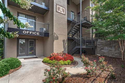 the entrance to an office building with a sidewalk and plants