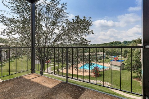 a balcony with a view of a pool and trees