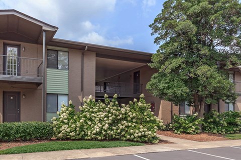 an apartment building with flowering bushes in front of it