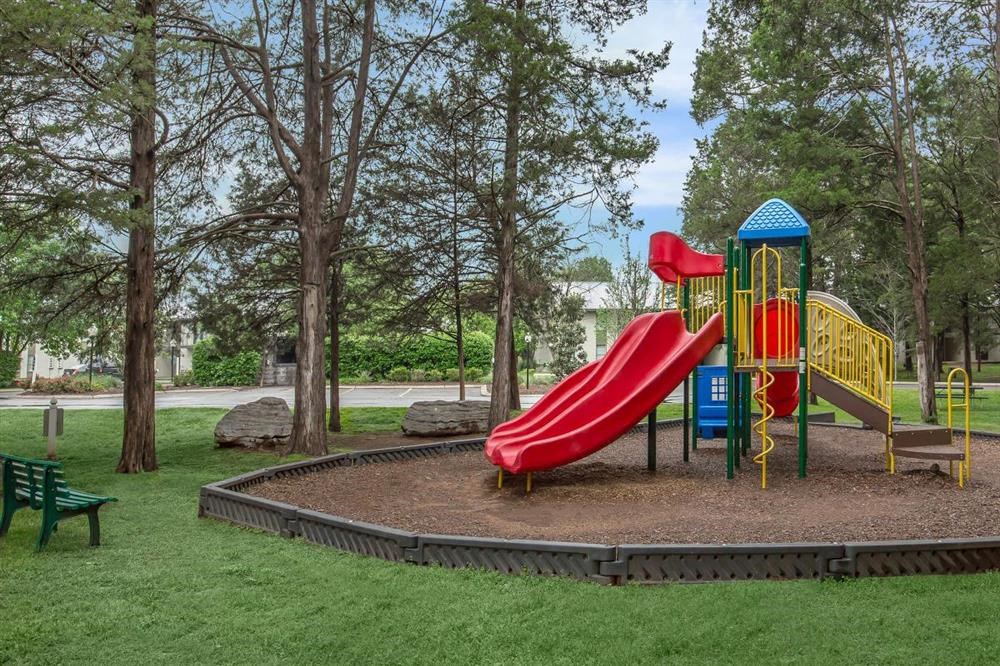 a playground with a red slide and a blue and yellow play structure