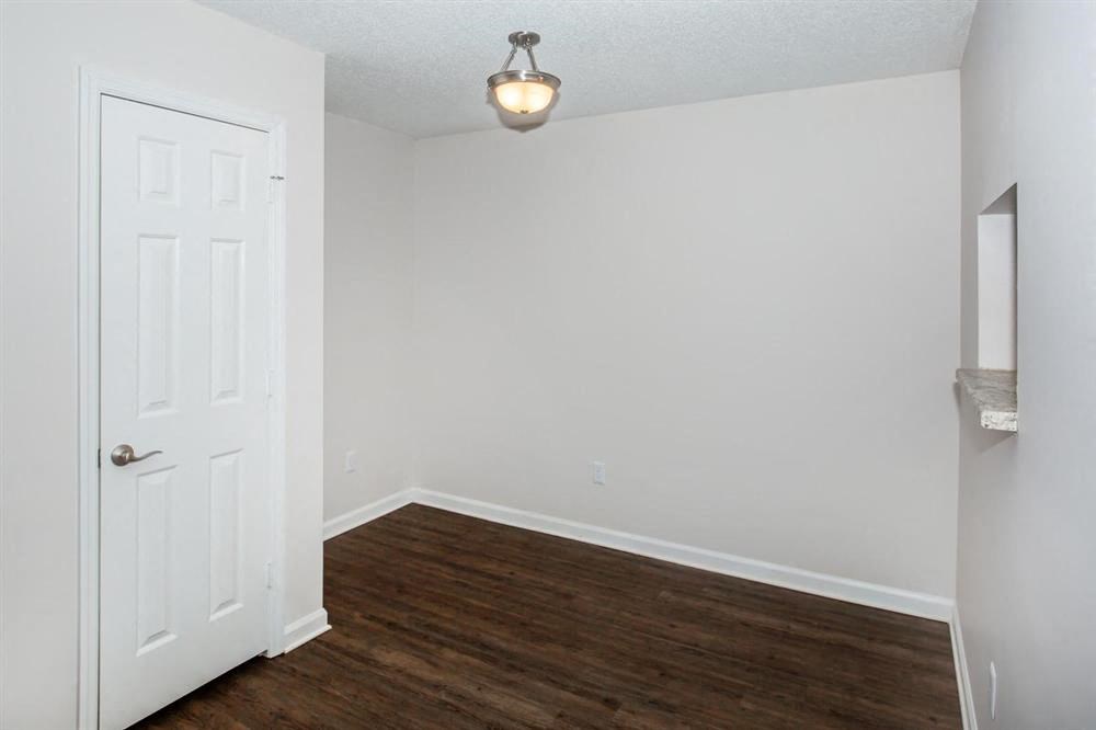 an empty living room with a white door and wood floors