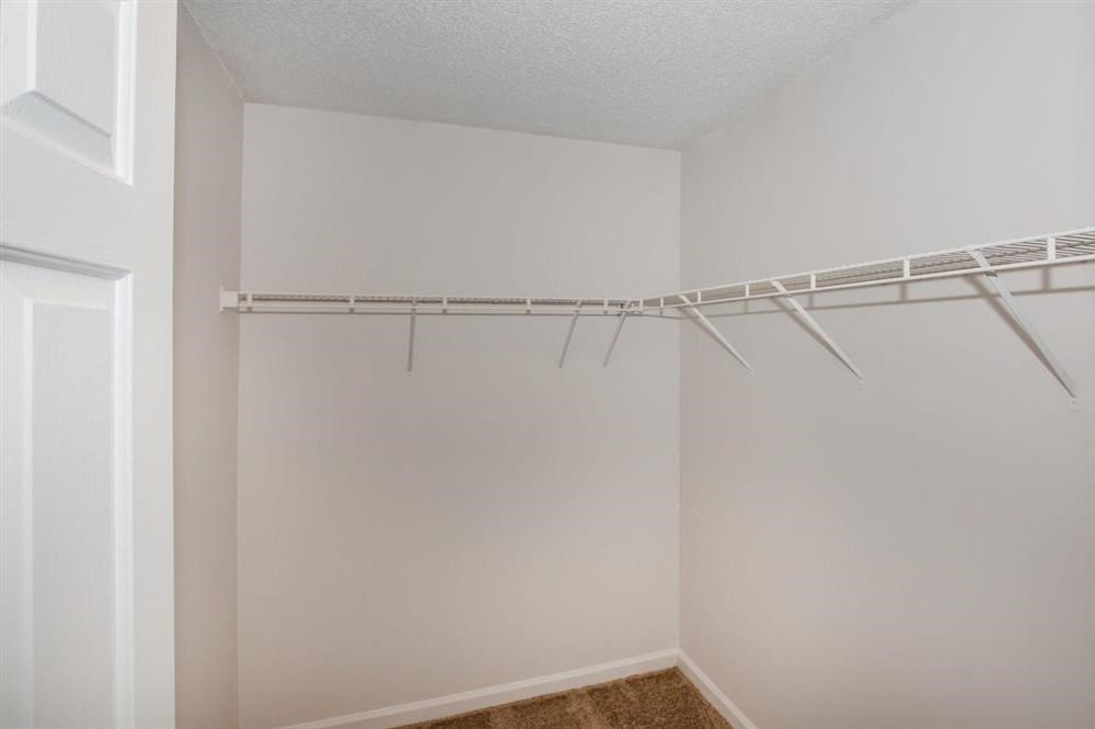 the closet in the bedroom of an empty apartment with a hanging rack