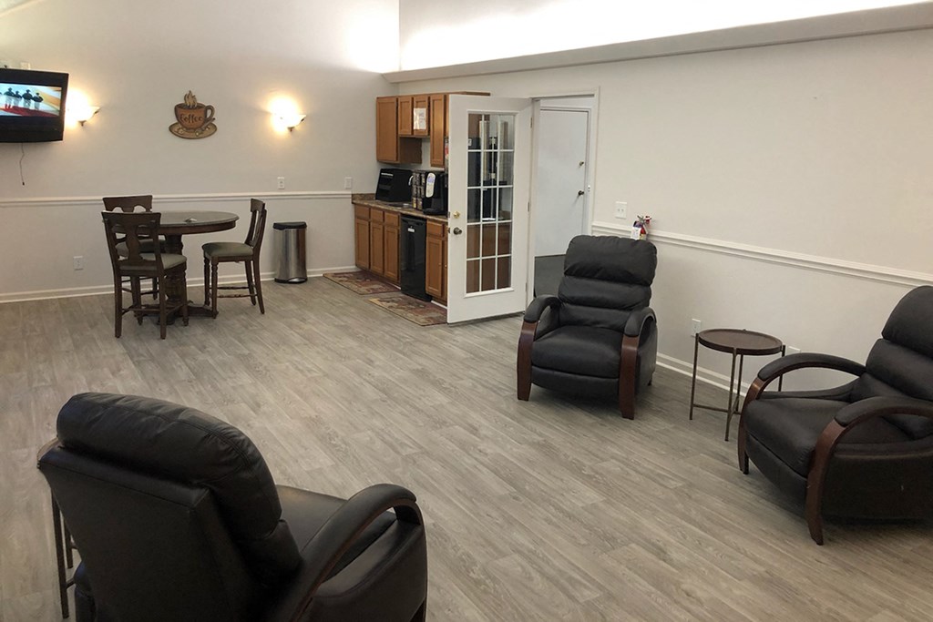 an empty living room with chairs and a kitchen