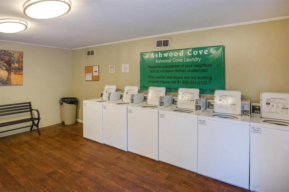 a row of washers and dryers in a room with a sign
