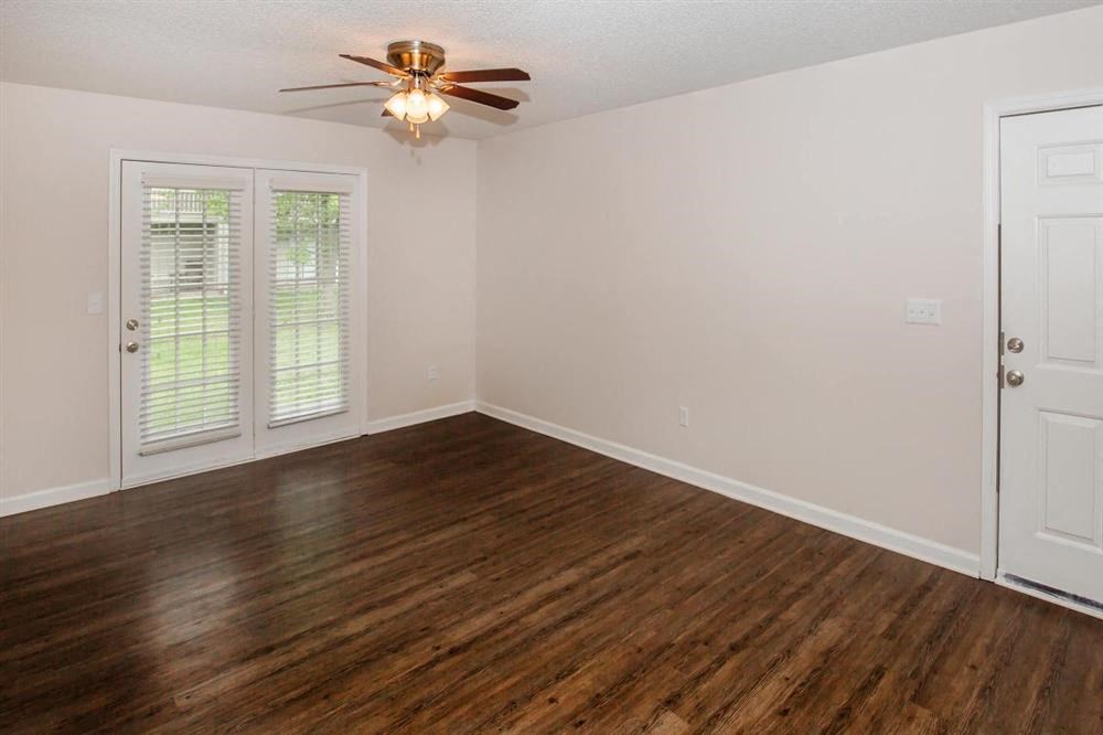 an empty living room with a ceiling fan and a door