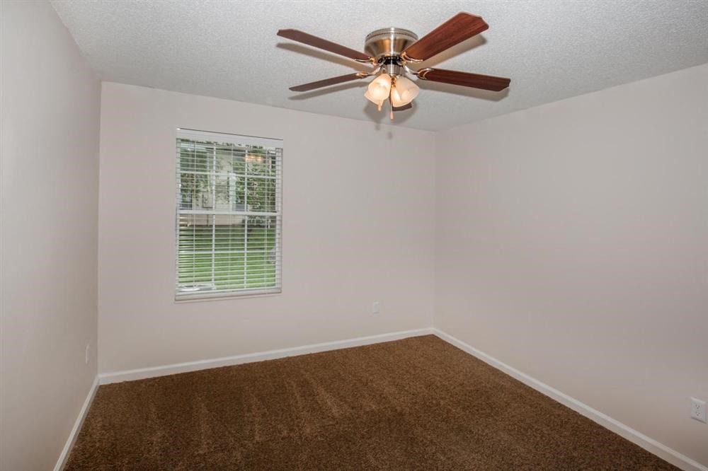 an empty bedroom with a ceiling fan and a window