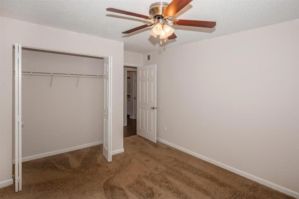 a bedroom with a ceiling fan and a closet