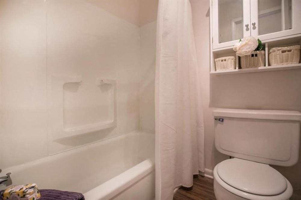 a white bathroom with a toilet and a bath tub