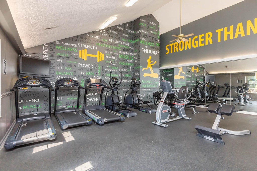 a gym with cardio equipment and a wall with strongerthan on it