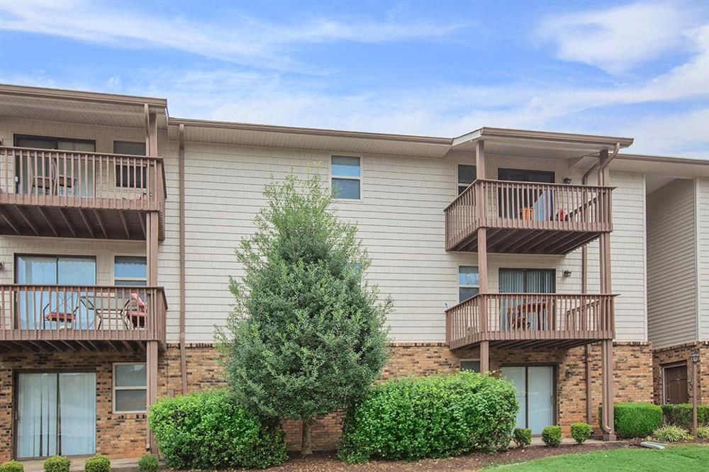 an apartment building with balconies and a tree in the yard
