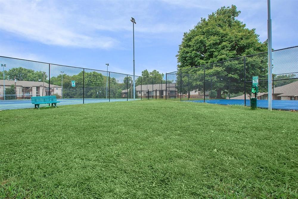 a park bench in the grass next to a fence