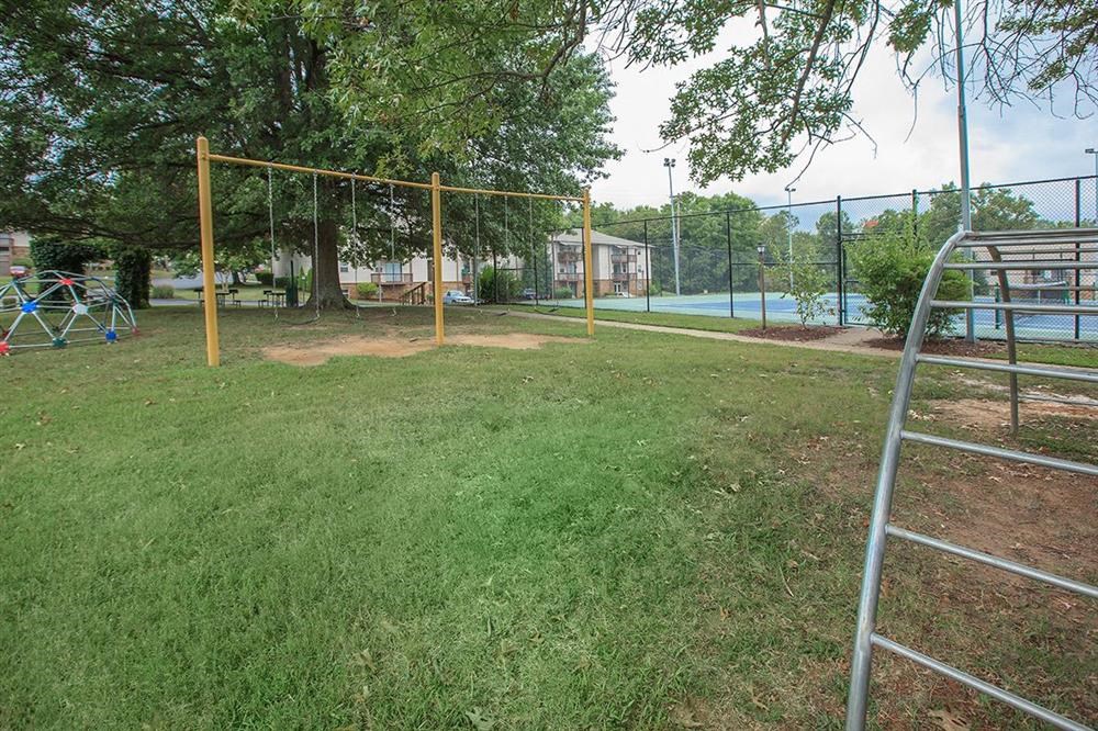 a park with a swing set and a ladder in the grass