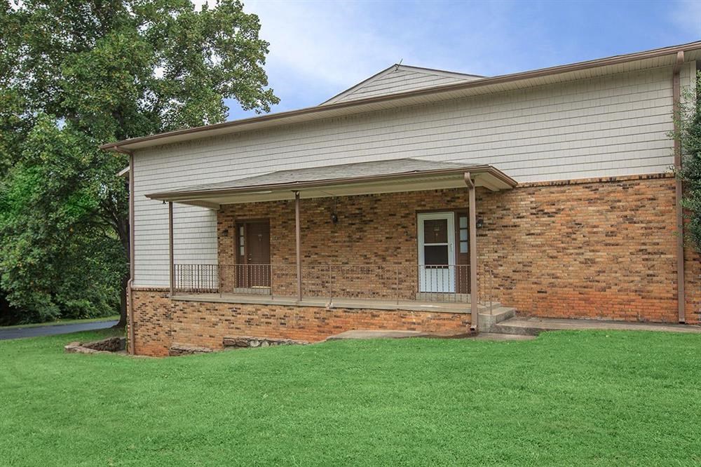 a brick house with a porch and green grass