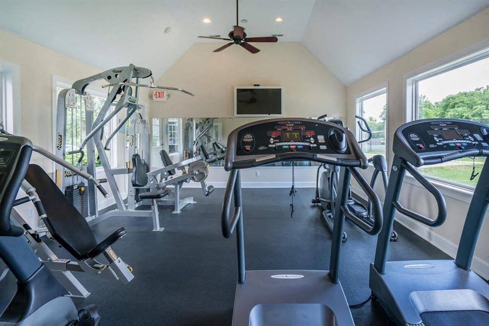 a gym with cardio equipment and a ceiling fan