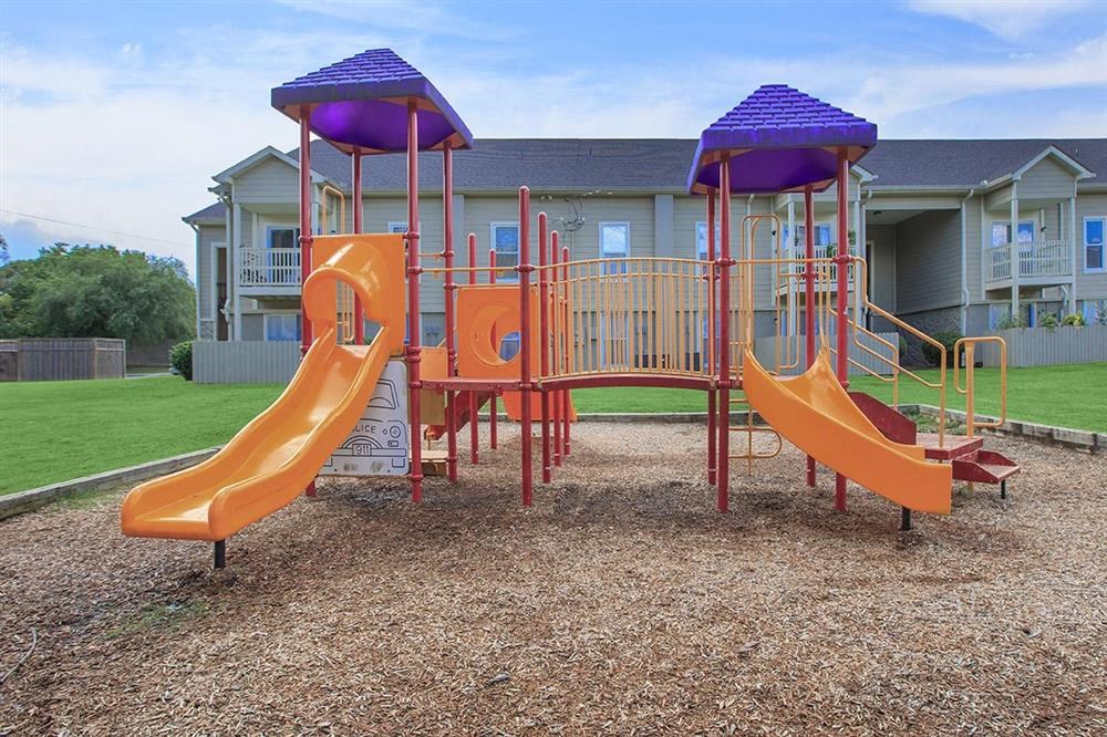 a playground with slides and a house in the background